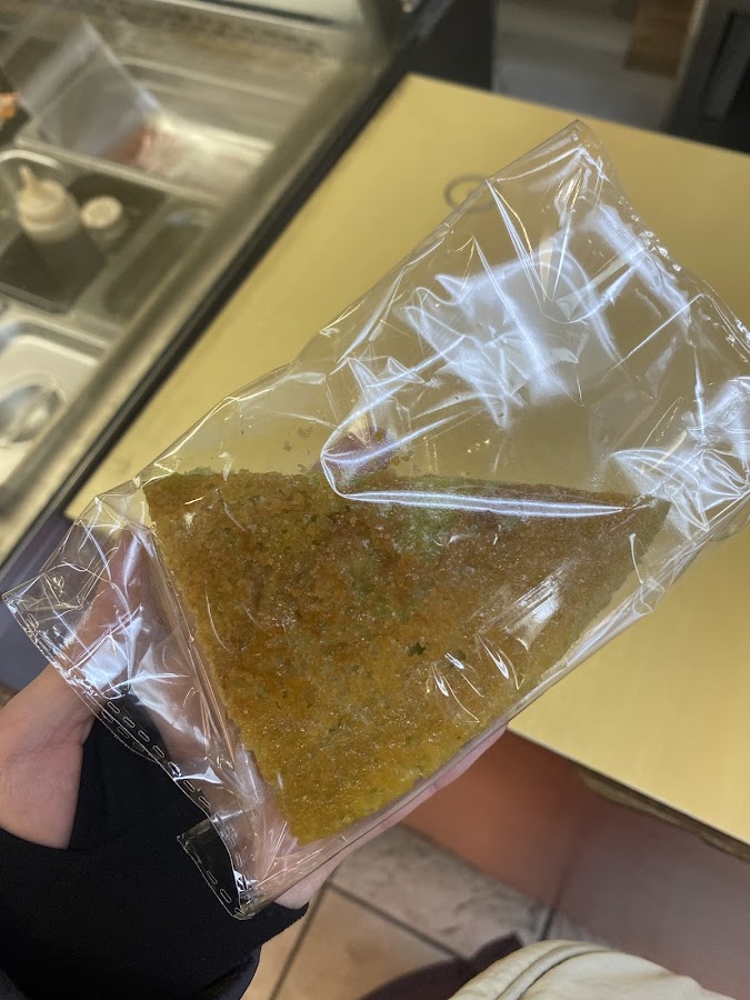 Packaged green cake held near counter